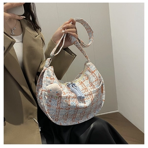 Détail du sac demi-lune en tweed avec texture tissée bleue et blanche et breloque