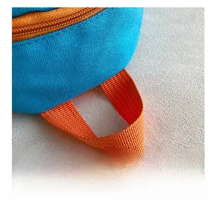 Détail de la poignée en toile orange et de la fermeture éclair du sac à dos bleu