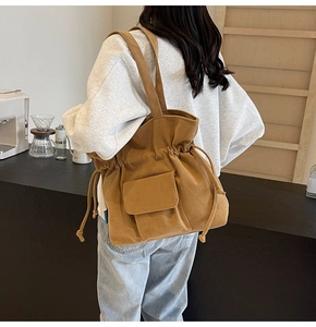 Detail of brown corduroy tote bag with drawstring closure and front flap pocket