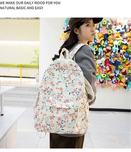 Détail du sac à dos Oxford fleuri avec poche zippée et pendentif à pompon blanc sur le côté