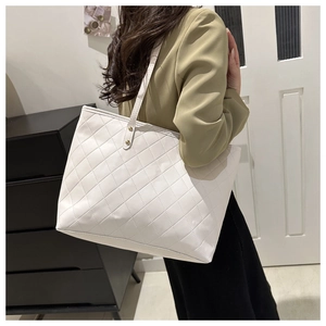 Detail view of white quilted tote bag featuring gold rivet accents and large capacity