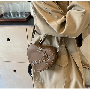 Detail of heart-shaped brown PU crossbody bag with silver rivets and dual zippers
