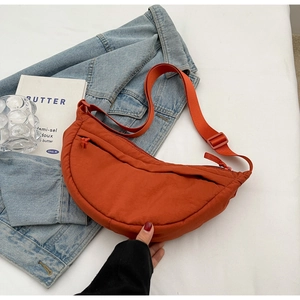 Detail view of water-resistant orange crescent bag with adjustable strap and zipper pocket