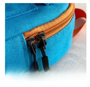 Détail de la fermeture éclair orange et curseurs noirs sur sac en toile bleue