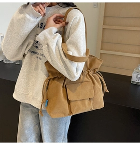 Detail of khaki corduroy tote bag featuring side drawstrings and a front flap pocket