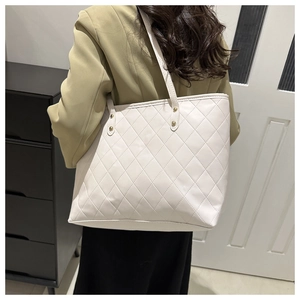 Rear view of a model wearing a white quilted PU leather tote bag with gold hardware detail