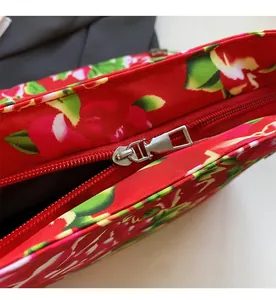 Close-up of smooth silver metal zipper on red floral canvas shoulder bag
