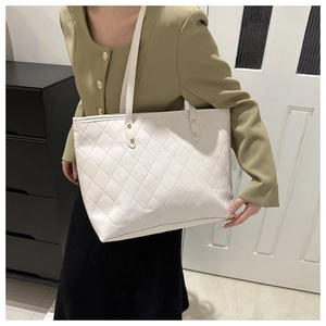 Detailed view of white quilted tote bag with gold rivets and spacious interior design