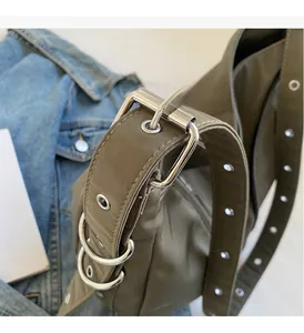 Detail of silver metallic buckle and high-density nylon strap on olive green crossbody bag