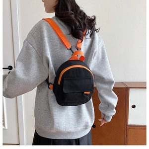 Mini sac à dos en toile noir et orange porté sur le dos par un mannequin femme