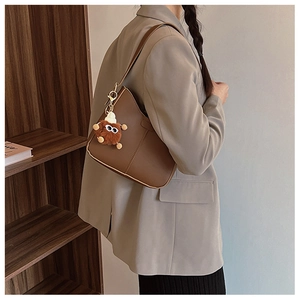 Detail of brown PU shoulder bag featuring a cute furry charm and gold metal hook