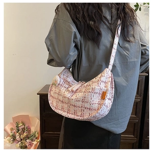 Détail du sac hobo en tweed rose et blanc avec texture et étiquette de mode sur le côté
