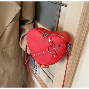 Close-up of a red heart-shaped PU leather crossbody bag with silver rivets and metal buckle