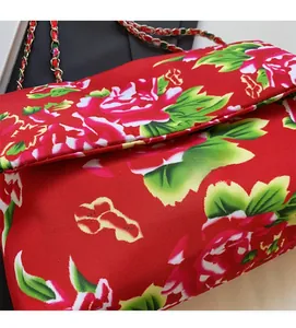 Detail of red floral canvas bag with gold chain strap and traditional peony print texture