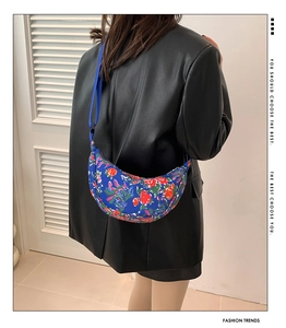Detail of blue nylon crossbody bag with red rose and dragon pattern on model back