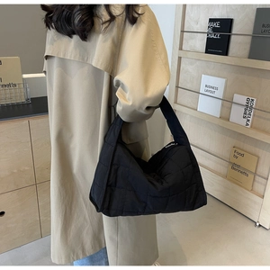 Quilted black puffer tote bag shown on model highlighting its soft texture and large capacity