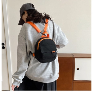 Détail d'un mini sac à dos en toile noir et orange porté par un mannequin de dos