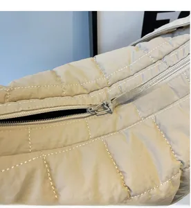 Detail view of the smooth zipper closure and square quilted fabric on beige crossbody bag