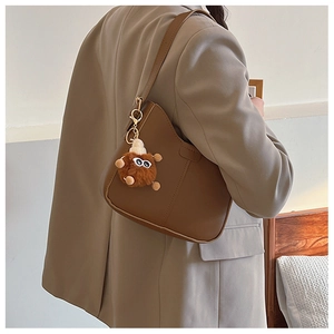 Brown PU leather shoulder bag featuring a fuzzy monster charm and golden hardware detail