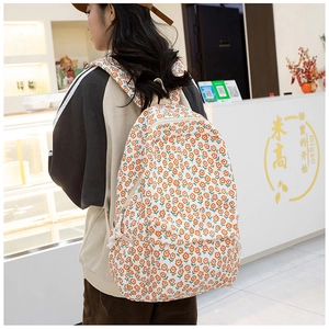 Détail du sac à dos fleuri sur modèle montrant la texture toile et les poches zippées