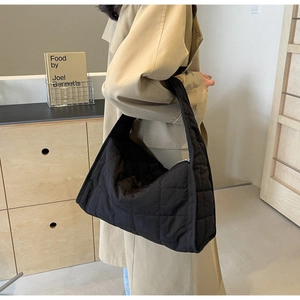 Detail of black quilted shoulder bag featuring premium nylon texture and wide strap design