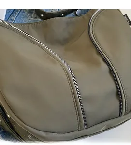 Close-up of olive green nylon bag showing soft fabric texture and metal rivet detail