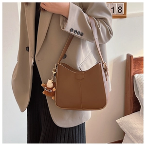 Detail of brown matte leather hobo bag with vertical stitching and cute bear charm