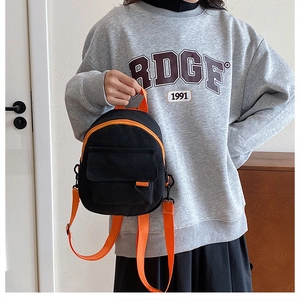 Détail du mini sac à dos en toile noire avec bretelles orange et poche avant à rabat