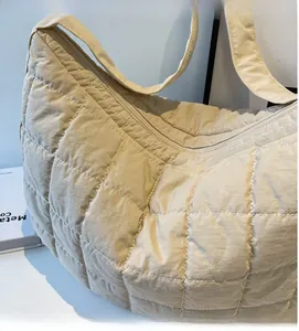 Close-up of beige quilted nylon shoulder bag showing soft diamond stitched texture
