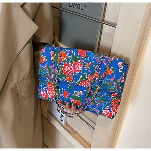 Detail of blue floral canvas shoulder bag with silver metal chain and envelope flap design