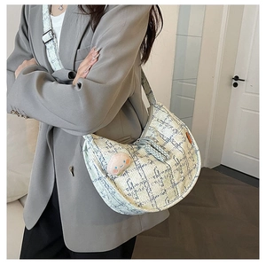 Détail d'un sac d'épaule en tweed à carreaux avec breloque pêche porté par un mannequin