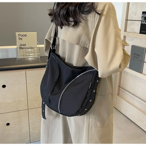 Detail view of the black nylon crossbody bag featuring curved zipper and metal eyelet details