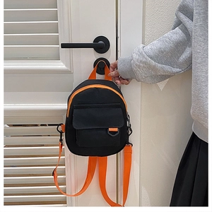 Détail d'un sac à dos en toile avec sangles orange et poche frontale sur une poignée