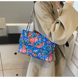 Detail view of ethnic floral canvas crossbody bag with silver chain strap and peony patterns
