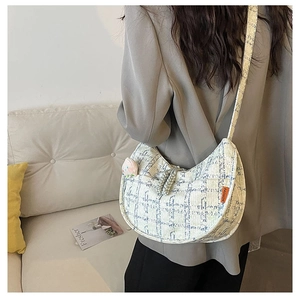 Détail du sac demi-lune en tweed à carreaux avec étiquette orange et breloque pêche en peluche