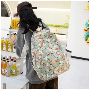 Détail du sac à dos en toile à motif marguerite avec tirettes de zip à pompon blanc