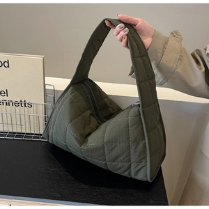 Detail of dark green quilted shoulder bag in padded nylon material with wide strap