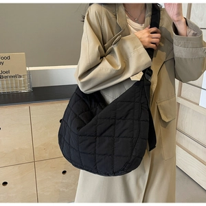 Close-up of black quilted canvas crossbody bag with adjustable wide strap and hardware