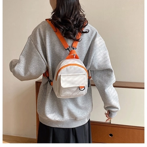 Détail d'un mini sac à dos en toile blanche avec des fermetures éclair orange vif