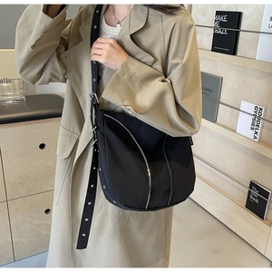 Detail shot of black crescent shoulder bag with silver zipper and eyelet strap