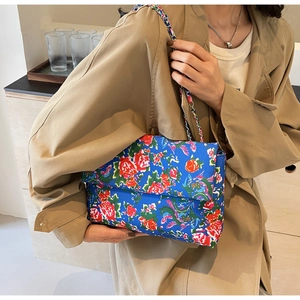 Detailed close-up of a blue floral canvas shoulder bag with red rose pattern on a trench coat
