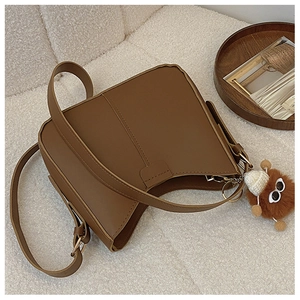 Brown PU leather crossbody bag with adjustable strap and cute plush toy pendant charm