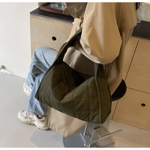 Detailed view of olive green quilted nylon tote bag worn by a model in casual winter outfit