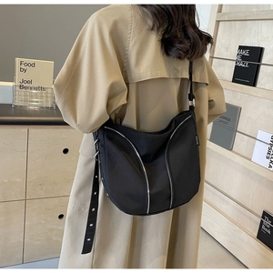 Detailed view of black hobo crossbody bag with silver zippers and adjustable strap
