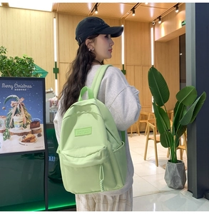 Détail d'un sac à dos en nylon vert clair avec plusieurs poches et un écusson logo