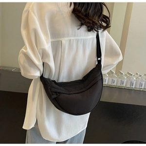 Model wearing a minimalist black nylon crescent crossbody bag with adjustable strap