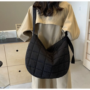 Detail of black quilted puffer crossbody bag with diamond stitching and wide strap