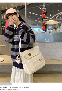 Vista dettagliata della borsa a tracolla in nylon bianco con ciondolo a cucciolo e ricamo