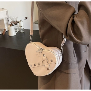 Detail of a beige heart-shaped PU leather crossbody bag with silver studs and metal ring