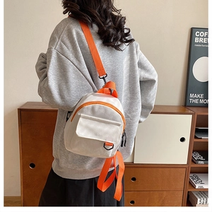 Détail du petit sac à dos en toile blanche avec des fermetures éclair orange vif